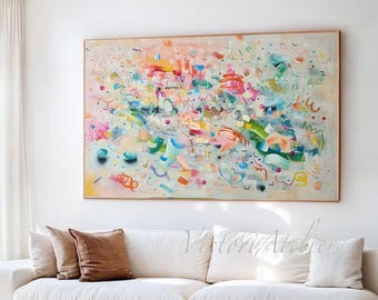 Puede incluir: Un salón moderno con una gran pintura abstracta enmarcada. La pintura presenta una vibrante mezcla de colores. También se ven un sofá blanco, una mesa de centro de madera y una silla de cuero.