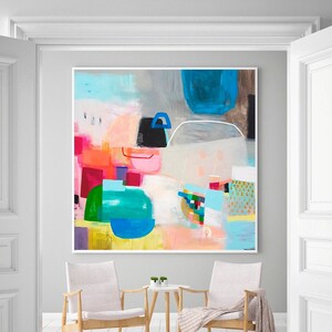 Op de afbeelding: Abstract schilderij met felle kleuren, waaronder roze, blauw, groen en geel, in een moderne woonkamer met twee stoelen en een kleine tafel.