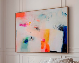 May include: Abstract painting with bright colors, including pink, orange, yellow, blue, and green, on a white background. The painting is hanging on a white wall above a white couch and a black coffee table.