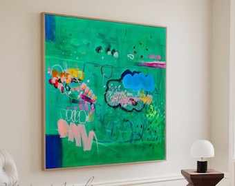 May include: Abstract painting with a green background, blue and pink clouds, and colourful details. The painting is framed and hanging on a white wall.