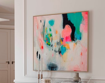 Peut inclure: Peinture abstraite aux couleurs vives, dont le rose, le bleu, le vert et le jaune, sur fond blanc. La peinture est encadrée d'un cadre doré et est accrochée à un mur blanc au-dessus d'une console noire.