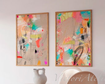 May include: Two abstract paintings in wooden frames with colourful brushstrokes and geometric shapes on a beige background. The paintings are hanging on a white wall above a wooden table with two chairs.