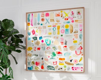 Puede incluir: Una gran pintura de acuarela enmarcada con una colección de formas y formas abstractas coloridas. La obra de arte incluye varios colores como rosa, azul, amarillo y verde. El marco es de color marrón claro. La pintura se exhibe en una pared blanca.