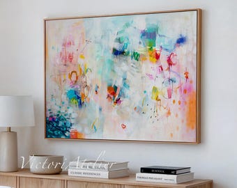 Peut inclure: Peinture d'art abstrait avec un cadre en bois. L'œuvre présente un mélange vibrant de couleurs, notamment le bleu, le rose, l'orange et le jaune, créant une composition dynamique. Le tableau est accroché au-dessus d'un meuble en bois avec une lampe et des livres.
