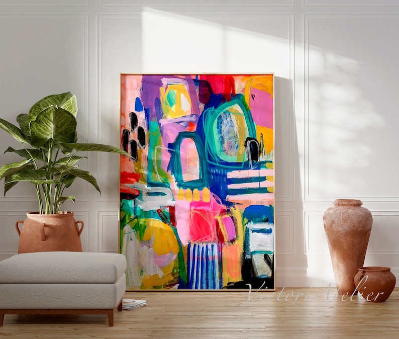 May include: Abstract painting with bold strokes of colour, including pink, blue, green, yellow, and black. The painting is framed in a gold frame and is hanging on a white wall.