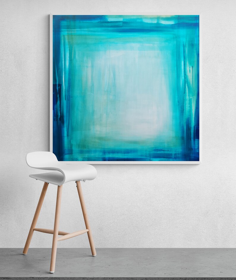 Pode incluir: Impress&atilde;o de arte abstrata com uma composi&ccedil;&atilde;o quadrada em tons de verde-azulado e turquesa, emoldurada em branco. Uma moderna banqueta branca com pernas de madeira est&aacute; posicionada em frente &agrave; obra de arte, criando uma est&eacute;tica minimalista.