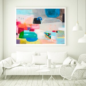 Op de afbeelding: Abstract schilderij met een witte achtergrond en kleurrijke geometrische vormen in tinten roze, blauw, groen en geel. Het schilderij is ingelijst in een wit frame en hangt aan een witte muur.