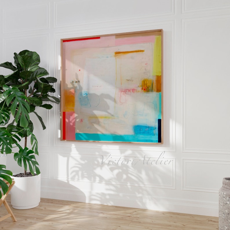 Puede incluir: Pintura abstracta con fondo blanco y formas geom&eacute;tricas coloridas en tonos de rosa, amarillo, azul y naranja. La pintura est&aacute; enmarcada en un marco de madera claro.
