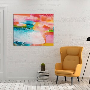 May include: Abstract painting with bright colors, including pink, blue, green, and yellow. The painting is hanging on a white wall in a room with a yellow armchair and a black tripod lamp.