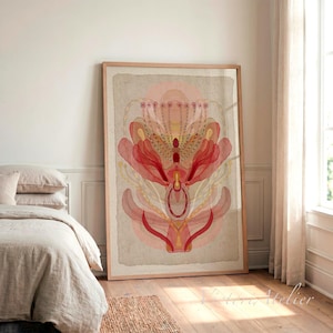 May include: A large rectangular framed wall art print featuring a symmetrical abstract floral illustration in shades of coral, peach, and cream. The artwork is set against a textured beige background with a deckled edge effect, displayed in a light wood frame.