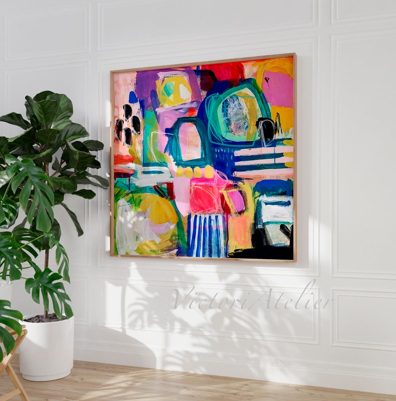 May include: Abstract painting with bold, colourful shapes and lines in shades of pink, yellow, blue, green, and black. The painting is framed in a light wood frame.