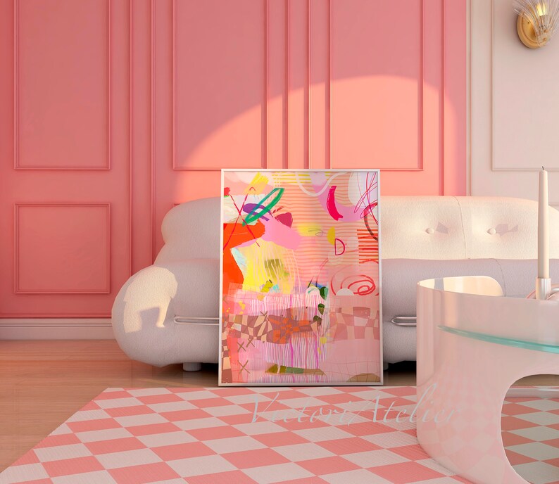 Op de afbeelding: Abstracte kunstprint met roze, gele, oranje, groene en blauwe kleuren. De print is ingelijst en hangt aan een roze muur boven een witte bank.