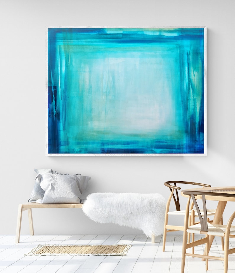 Pode incluir: Arte de parede abstrata com uma composi&ccedil;&atilde;o retangular de tons turquesa e azul sobrepostos. A obra de arte &eacute; emoldurada em branco e pendurada em uma parede branca. O quarto tamb&eacute;m inclui um banco de madeira, almofadas e um tapete.