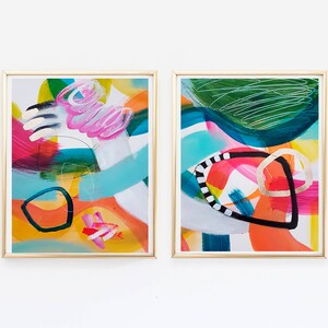 Puede incluir: Dos pinturas abstractas enmarcadas con pinceladas coloridas y formas geom&eacute;tricas. Las pinturas est&aacute;n en marcos dorados y tienen un fondo blanco.