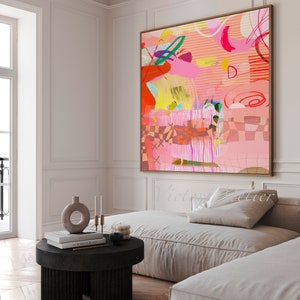 Op de afbeelding: Abstract schilderij met een kleurenschema in roze, rood, geel, groen en blauw. Het schilderij is ingelijst in een licht houten lijst en hangt aan een witte muur.