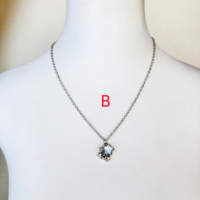May include: A silver chain necklace with a star-shaped pendant featuring a white iridescent center. The pendant is made up of multiple smaller stars.