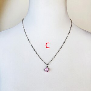 May include: A silver chain necklace with a pink flower pendant.