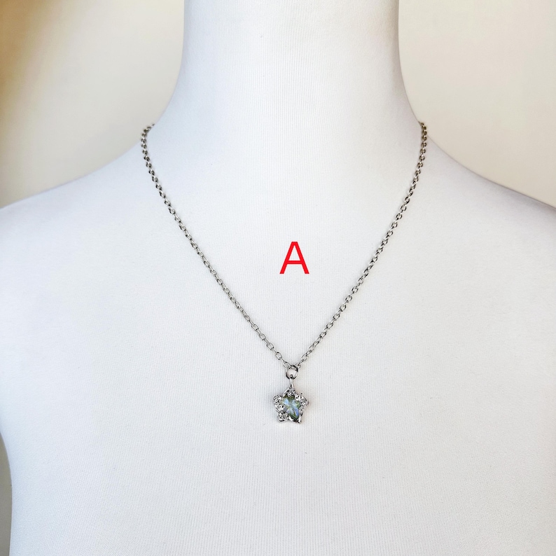 May include: A silver chain necklace with a star-shaped pendant featuring a clear crystal in the center.