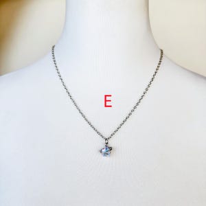 May include: A silver chain necklace with a small, clear crystal pendant in the shape of a butterfly.