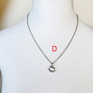 May include: A silver chain necklace with a small, silver, star-shaped pendant.