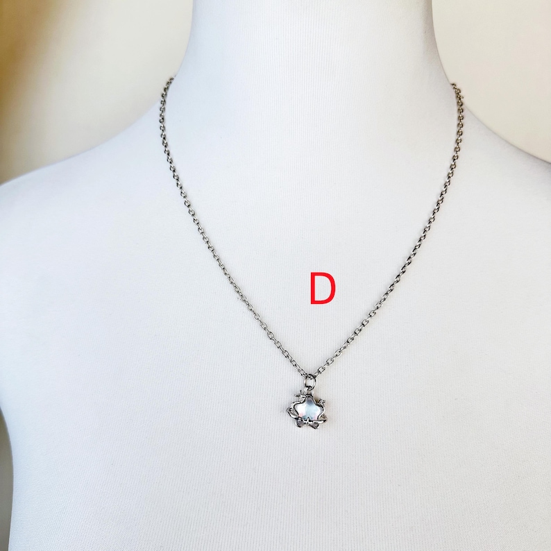 May include: A silver chain necklace with a small, silver, star-shaped pendant.