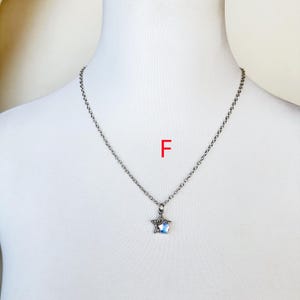 May include: A silver chain necklace with a star-shaped pendant featuring a clear crystal. The pendant is set in a silver frame.