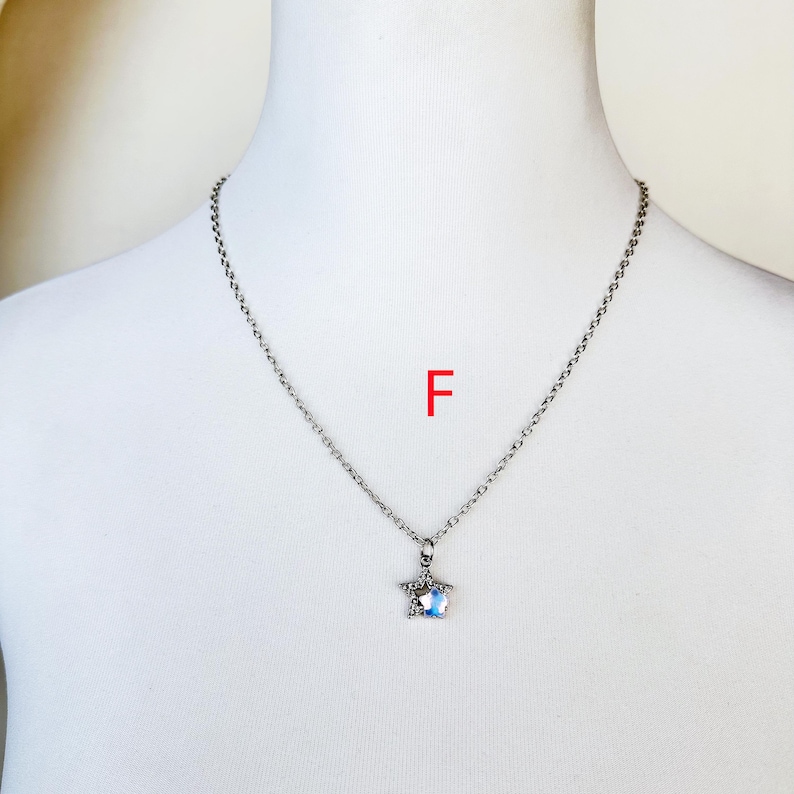 May include: A silver chain necklace with a star-shaped pendant featuring a clear crystal. The pendant is set in a silver frame.