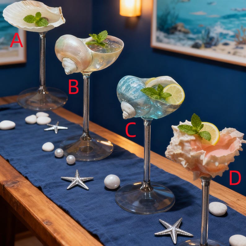 May include: Four unique cocktail glasses, each crafted from a different seashell, are displayed on a wooden table with a blue runner. The glasses are filled with drinks and garnished with mint and lemon slices. Decorative starfish and pearls are scattered around.