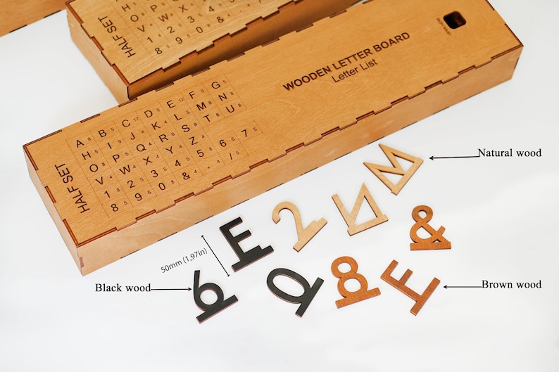 K&ouml;nnte beinhalten: Eine h&ouml;lzerne Aufbewahrungsbox f&uuml;r ein Buchstabenbrett mit aufgedruckter Buchstabenliste und einem Set aus einzelnen Buchstaben, Zahlen und Symbolen aus schwarzem, braunem und naturfarbenem Holz. Eine Ma&szlig;angabe zeigt eine H&ouml;he von 50 mm.