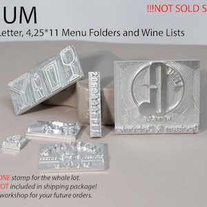 Könnte beinhalten: Ein Satz Metall-Stempel zum Erstellen von individuellen Menümappen und Weinkarten. Die Stempel sind aus silbernem Metall und haben verschiedene Designs, darunter ein Weinglas, eine Musiknote und einen dekorativen Rand. Die Stempel sind auf einer hellbraunen Oberfläche angeordnet. Der Text "MEDIUM" ist oben im Bild sichtbar. Der Text "NOT SOLD SEPARATELY" ist oben im Bild sichtbar.