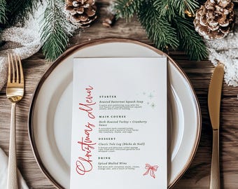 Op de afbeelding: Een witte rechthoekige kerstmenukaart met rode cursieve tekst en groene accenten, met secties voor voorgerecht, hoofdgerecht, dessert en drankje. De kaart is gecentreerd op een wit bord met een gouden vork en mes aan weerszijden.