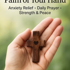 May include: A hand-carved wooden prayer cross with a heart-shaped cutout, held in an open palm. The cross is dark brown and the image includes the text "Comfort in the Palm of Your Hand" and "Anxiety Relief &bull; Daily Prayer &bull; Strength & Peace."