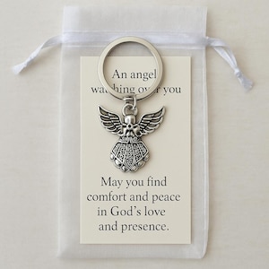 May include: A silver angel keychain with a detailed wing and body design, attached to a keyring. The keychain is presented with a card inside a white organza bag. The card reads, "An angel watching over you. May you find comfort and peace in God's love and presence."