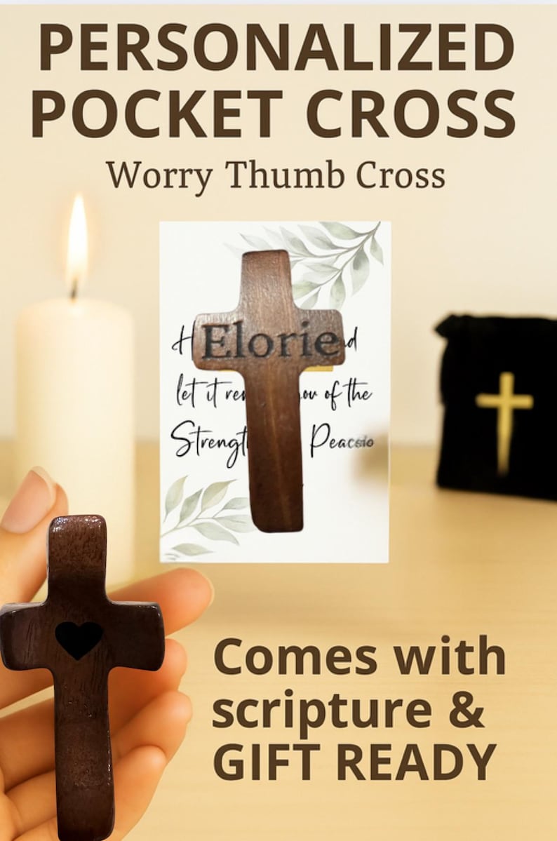 May include: A wooden pocket cross with a heart cutout, displayed with a card and a small black bag. The cross is dark brown and has the word "Eloried" on it. The text "Comes with scripture & GIFT READY" is also visible.