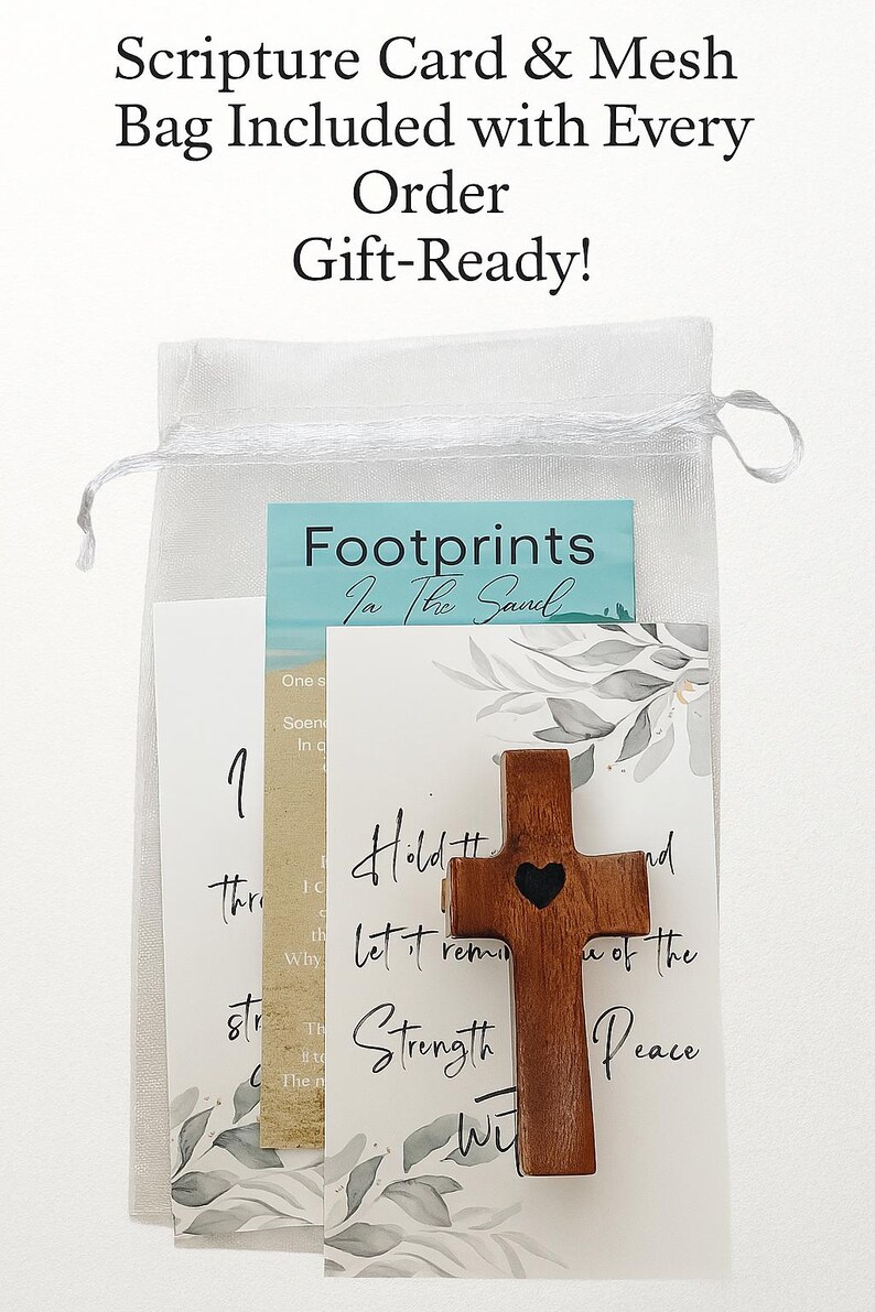 May include: A wooden cross with a heart cutout, included with scripture cards and a mesh bag. The cards have text that reads "Footprints in the Sand", "Hold and Let it remind you of the Strength and Peace". The bag is white.