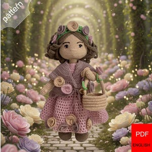May include: A crocheted doll wearing a pink dress, a shawl, and a floral headband. The doll is holding a small basket. The background is a blurred garden path with flowers. The image has the word "pattern" in the top left corner and "PDF ENGLISH" in the bottom right corner.