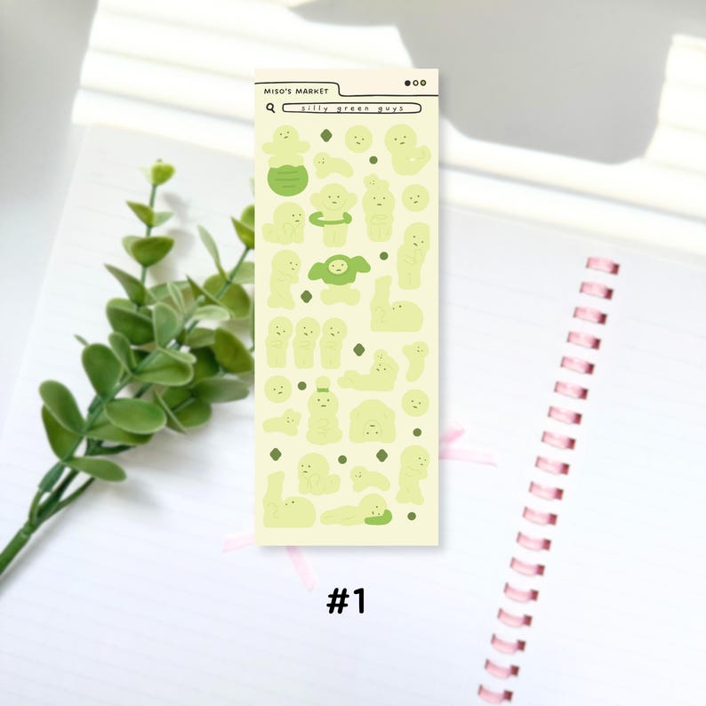 Puede incluir: Una hoja de pegatinas con varios personajes y formas de dibujos animados de color verde claro. La hoja incluye el texto "Miso's Market" y "silly green guys" en un dise&ntilde;o de barra de b&uacute;squeda. El n&uacute;mero "#1" est&aacute; impreso en la parte inferior. Las pegatinas est&aacute;n sobre un fondo blanco.