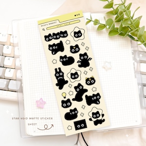 May include: A matte sticker sheet featuring black cat and star illustrations. The sheet includes the text "Miso's Market" and "star void". The stickers are in various poses and shapes, with a light yellow background.