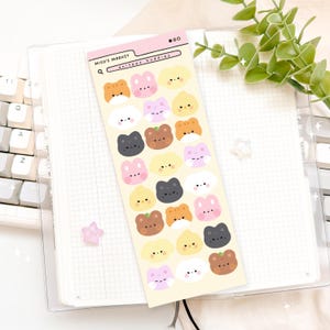 May include: A sticker sheet featuring various cartoon animal faces in shades of brown, pink, yellow, and black. The sheet has the text "Miso's Market" and "oniteez buddies". The stickers are arranged on a light yellow background.