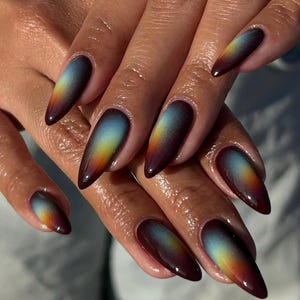 May include: A close-up of a set of long, almond-shaped nails. Each nail features a gradient design, transitioning from a deep burgundy at the tips, through shades of orange and yellow, to a light blue at the base. The nails are glossy and well-manicured.