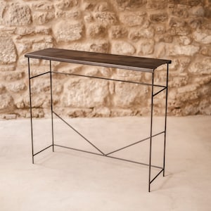 Puede incluir: Una mesa consola de metal negro con una tapa rectangular de madera. La mesa tiene un diseño simple y geométrico con una estructura de soporte triangular.