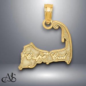 May include: Gold-colored pendant shaped like the outline of Cape Cod with the words "Cape Cod" inscribed on the pendant.