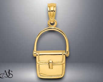 May include: A gold-colored purse pendant with a curved handle and a rectangular body. The pendant has a clasp closure and is designed with a detailed border. The bail is attached to the top of the handle.