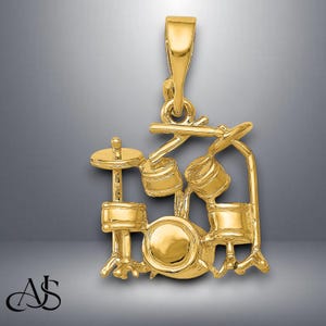 May include: Gold-tone pendant charm in the shape of a drum set. The charm features a bass drum, two tom-toms, and a cymbal.