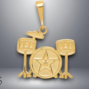 May include: Gold-tone pendant necklace featuring a detailed drum set design. The pendant includes a bass drum with a star in the center, two smaller drums, and a cymbal.