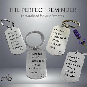 May include: Silver-colored dog tag keychains with engraved messages. Each tag has a different message, including "have fun, be safe, make good choices, call your grandma/mom/aunt/paw-paw." The text "THE PERFECT REMINDER" is at the top.
