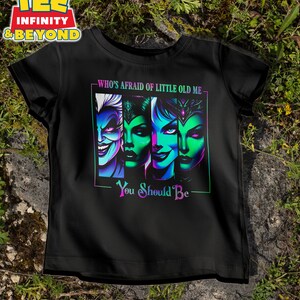May include: Black t-shirt featuring a colorful graphic of four stylized villainous faces with the text "WHO'S AFRAID OF LITTLE OLD ME - YOU SHOULD BE". The graphic has neon green, blue, and purple accents.