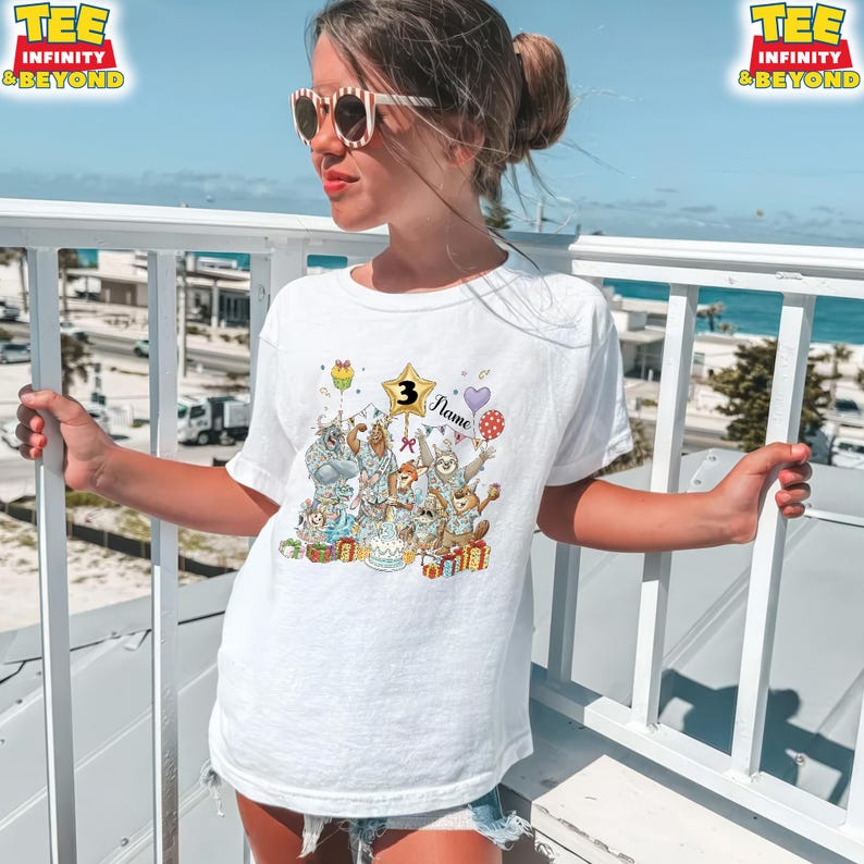 Puede incluir: Camiseta blanca con un gr&aacute;fico colorido de animales de dibujos animados celebrando un cumplea&ntilde;os. El gr&aacute;fico incluye una estrella con el n&uacute;mero 3, globos y el nombre "Flame". La camiseta tiene el texto "TEE INFINITY & BEYOND" en la parte superior.