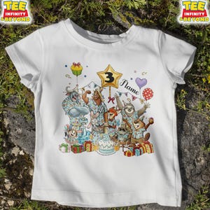Puede incluir: Camiseta blanca con una colorida ilustraci&oacute;n de animales de dibujos animados celebrando un cumplea&ntilde;os. El dise&ntilde;o incluye un globo en forma de estrella con el n&uacute;mero "3", una tarta, regalos y la palabra "Name".