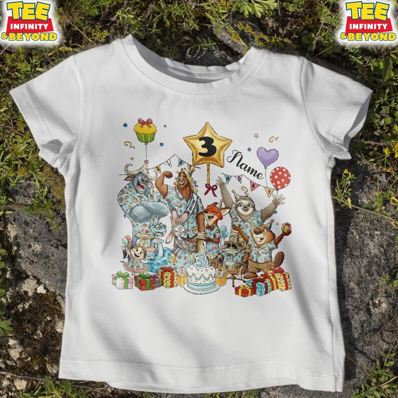 Puede incluir: Camiseta blanca con una colorida ilustraci&oacute;n de animales de dibujos animados celebrando un cumplea&ntilde;os. El dise&ntilde;o incluye un globo en forma de estrella con el n&uacute;mero "3", una tarta, regalos y la palabra "Name".
